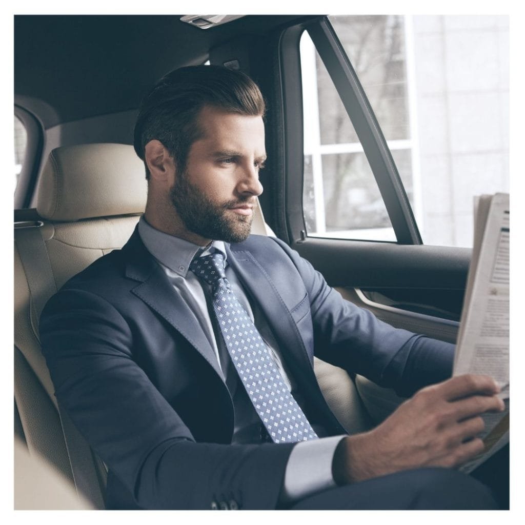 person reading in back of luxury car